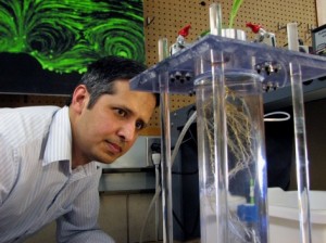 Zaki Jubery, a postdoctoral research associate in mechanical engineering, examines corn roots in a pressure chamber that measures the root system's water and nutrient flow. Photo by Mike Krapfl.