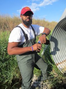 Maurice Washington collects a water sample from tile drains in the South Fork Watershed north of Ames, Iowa.