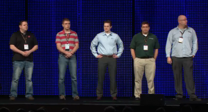 Nick (second from left) standing on stage waiting to receive his award. 