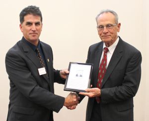 Dr. Andy Hillier, Reginald R. Baxter Endowed Department Chair of the Department of Chemical and Biological Engineering, presents Brady with his Hall of Fame plaque. A similar plaque is now on display on Sweeney Hall's Hall of Fame wall.