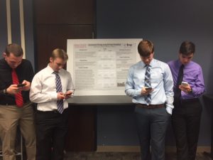 Bohle (far left) and his research team, with cell phones in hand, at the CCEE Freshman Research Initiative Poster Session (photo courtesy Peter Savolainen)