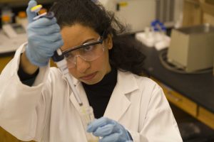 Da'Er uses a pipette while working with cultures in the lab.