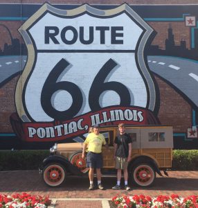 Christopher Gillis and Dr. T. Lindsay Baker stand in front of a mural painted outside of the Route 66 Association Hall of Fame and Museum in Pontiac, Illinois. 