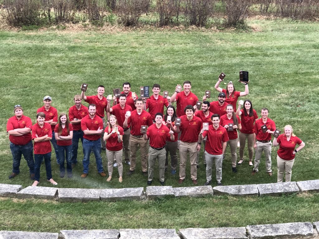 ISU ASC competition team gathers around to take a photo with their plaques from competition. 