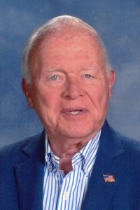 Headshot of Bill Gardiner on a blue background.