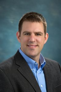 Headshot of Brian Anderson on a blue background.