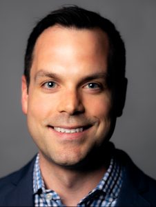 Headshot of Michael Anctil on a gray background.