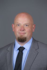 Headshot of Roy Sturgill on a gray background.