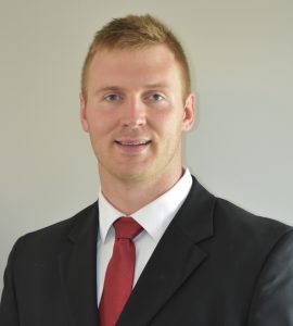 A headshot of mechanical engineering assistant professor Todd Kingston. He is smiling and wearing a suit and tie.