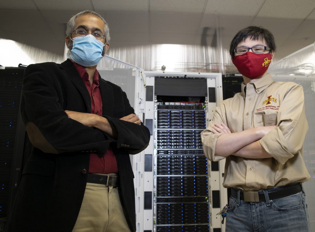 Mechanical engineering professor and student pose in front of a super computer inside Durham Hall