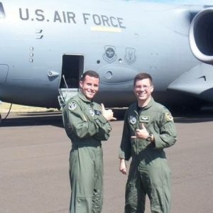 Two air force members pose in front of a plane