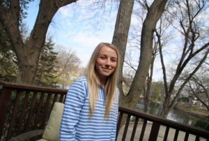 Photo of Emily Olson standing outside and smiling with trees in the background