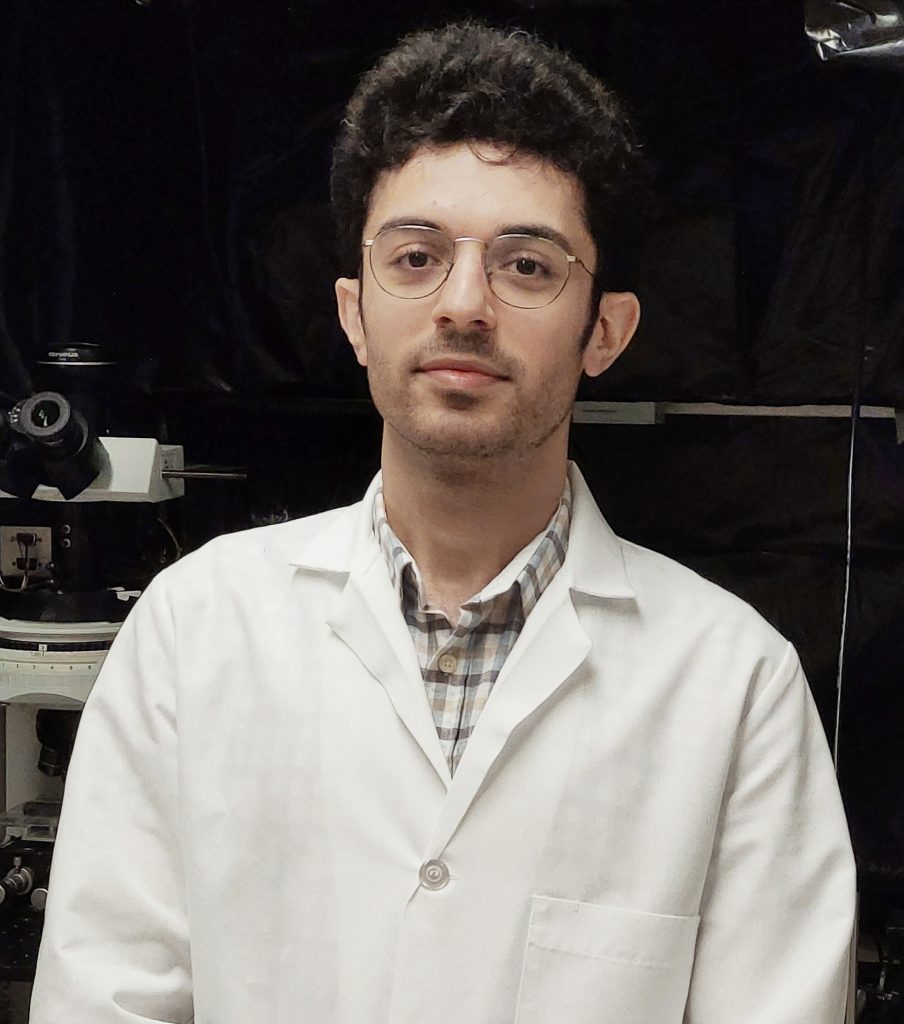 Shot of Hamidreza Zobeiri in a lab coat with lab equipment in the background