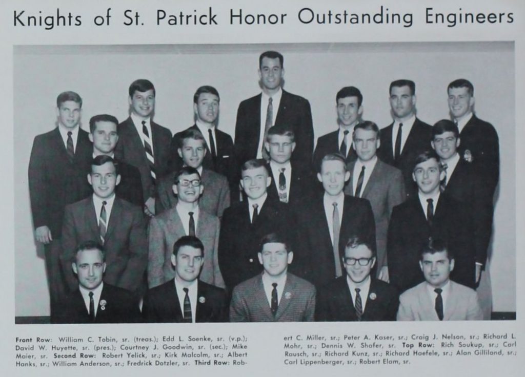 A black and white photo of men involved n the Knights of St. Patrick honorary society. All of the men in the shot are wearing suits and tie, and most of them are smiling at the camera.