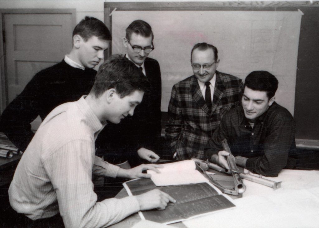 A black and white photo from the 1970s of four students and a professor. It appears the group is creating a scene from a plant design course.