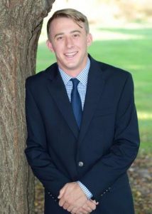 Andrew Whiteman standing next to a tree and smiling