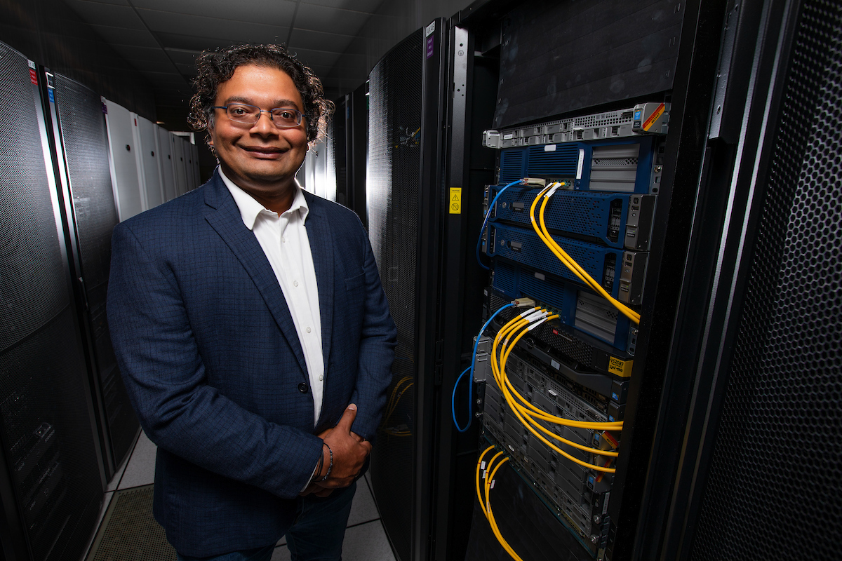 Baskar Ganapathysubramanian of Iowa State University stands next to some computing equipment.