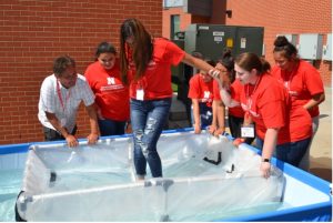 Cornelius stands with a group of students at a summer camp, and they are testing boat floatation