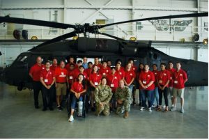 Cornelius surrounded by high school summer camp kids in front of a National Guard helicopter