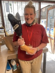 Mechanical engineering student Jillian Dunn smiles for the camera while holding up a prosthetic leg that she designed and fabricated as part of her work with the Range of Motion Project.