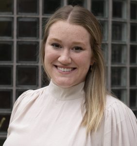 Mechanical engineering student Jillian Dunn poses outside of Black Engineering Building. Jillian is smiling and wearing a cream-colored blouse.