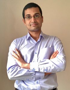 Mechanical engineering postdoctoral researcher poses with his arms crossed. He is wearing a light-colored collared shirt.