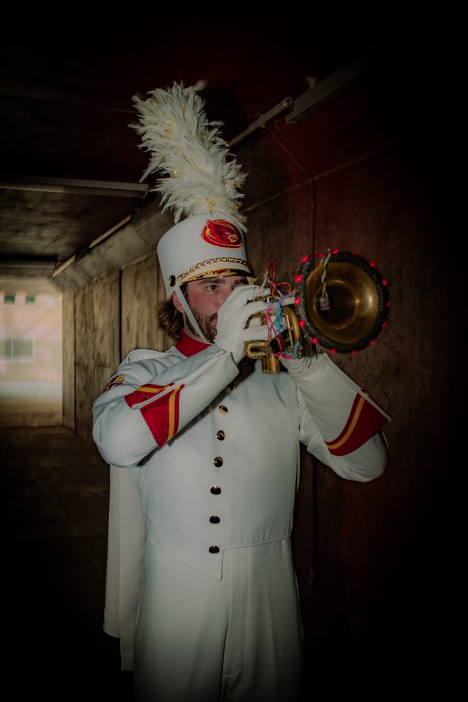 A student wearing a band uniform and playing a trumpet