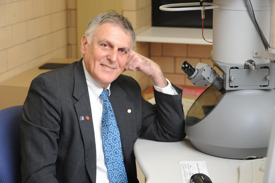 Dan Shechtman sits in front of a microscope