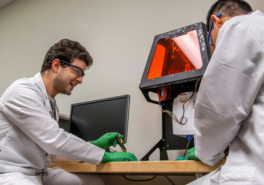 Ayman Karmi and Shan Jiang organize materials at a desk in the REFORM lab.