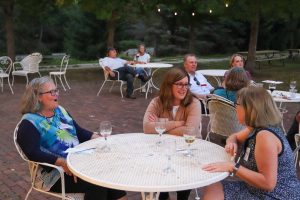 Three CCEE 150th attendees talk to each other over wine outside of Prairie Moon Winery.