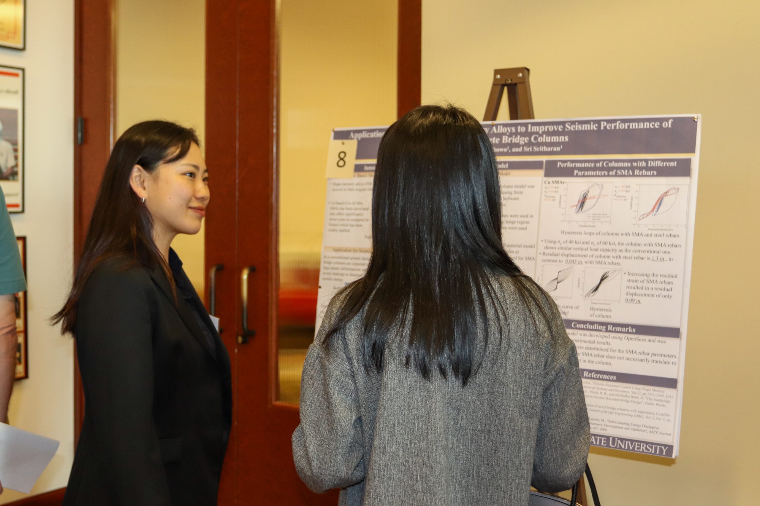 Two attendees talk with one another at the research symposium.