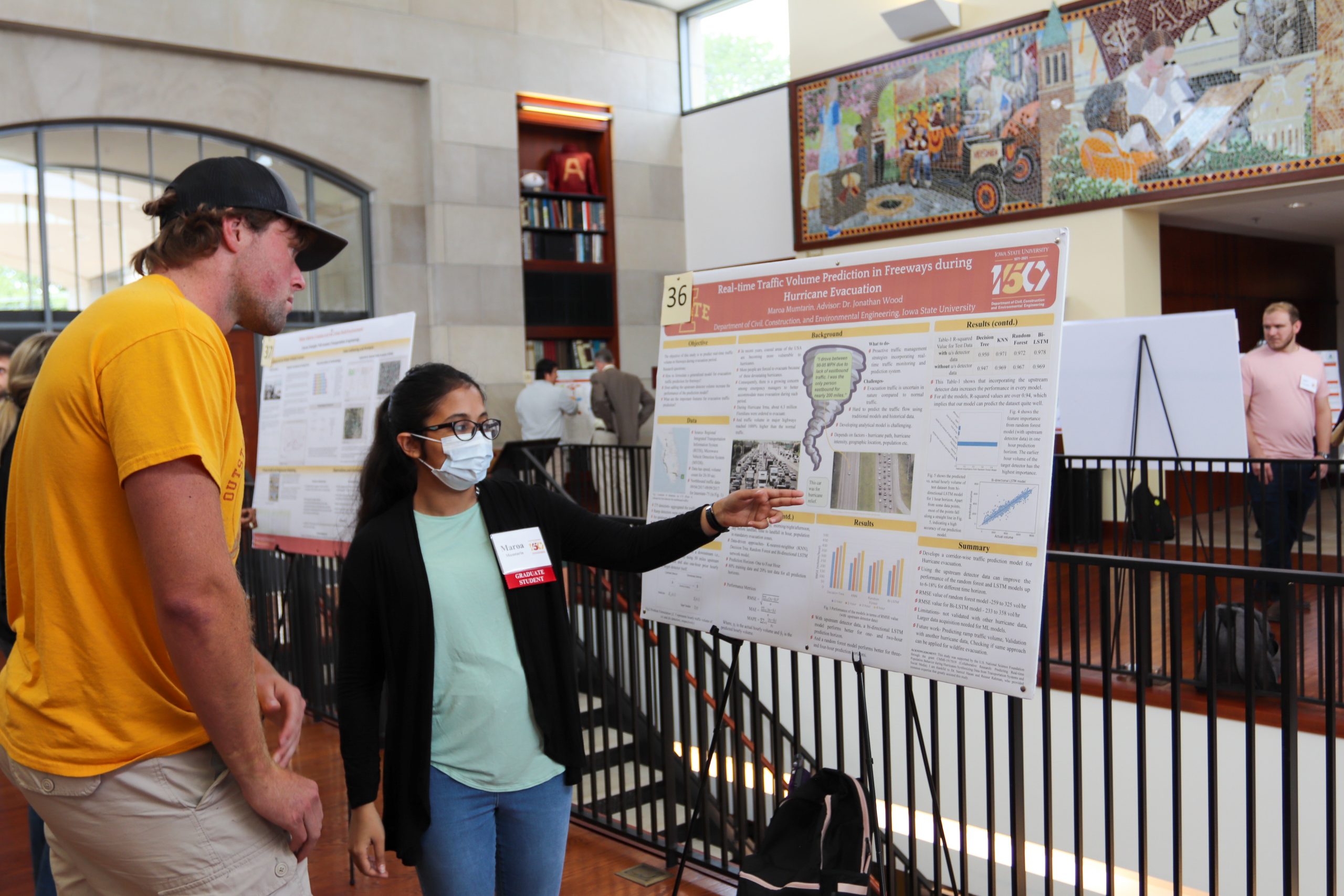 Two attendees of the research symposium discuss real-time traffic volume prediction.