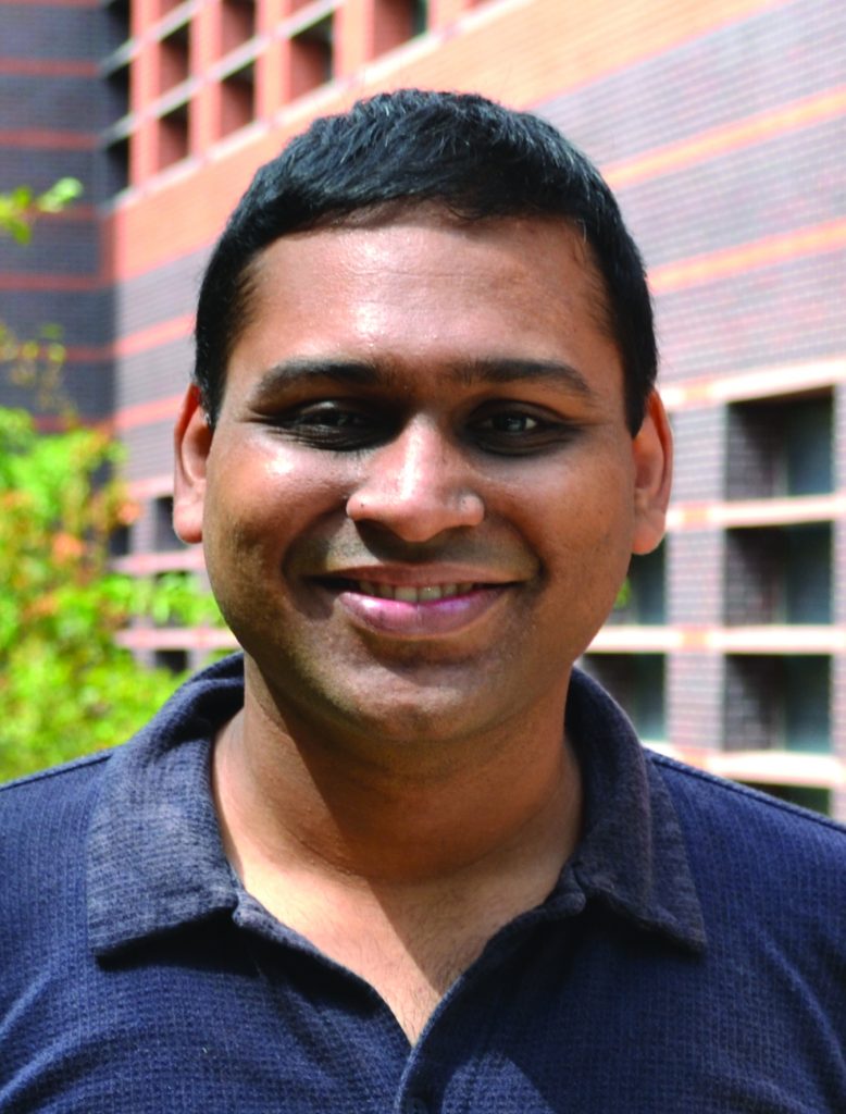 A mechanical engineering professor smiles and poses outside of Black Engineering Building