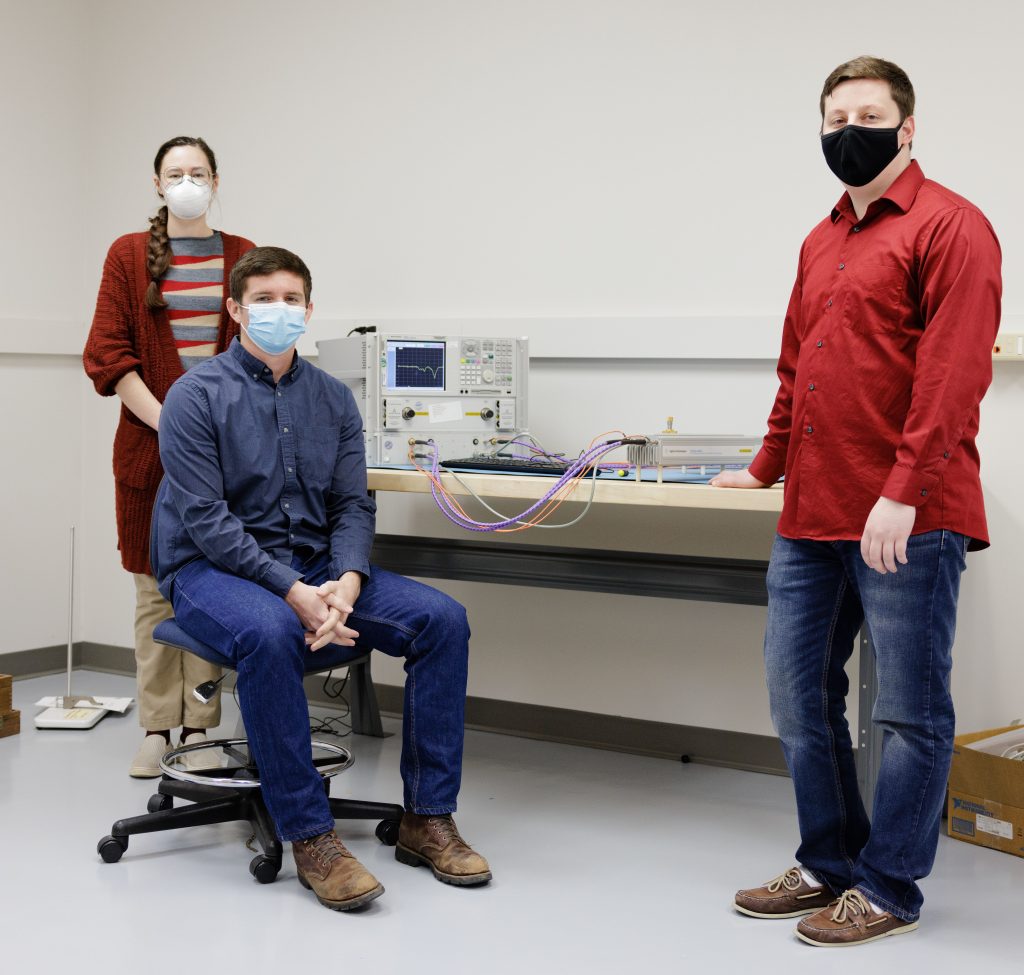 Three researchers post with a nondestructive evaluation instrument