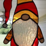 A stained glass elf. He is wearing red and yellow clothes.