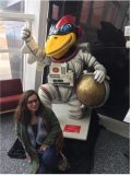A student poses next to a status of Cy - the Iowa State University mascot - dressed up like an astronaut.