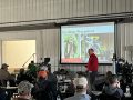 Photo of a crowded room and a speaker teaching about planter technology