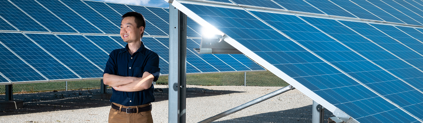 Zhaoyu Wang stands in front of a solar panel