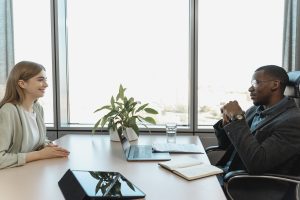 Man and woman sitting across from each other in office desk setting