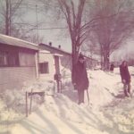 A photo of Larry and Pam standing outside of the Pammel Court living unit as an uncharacteristic April snow fall.