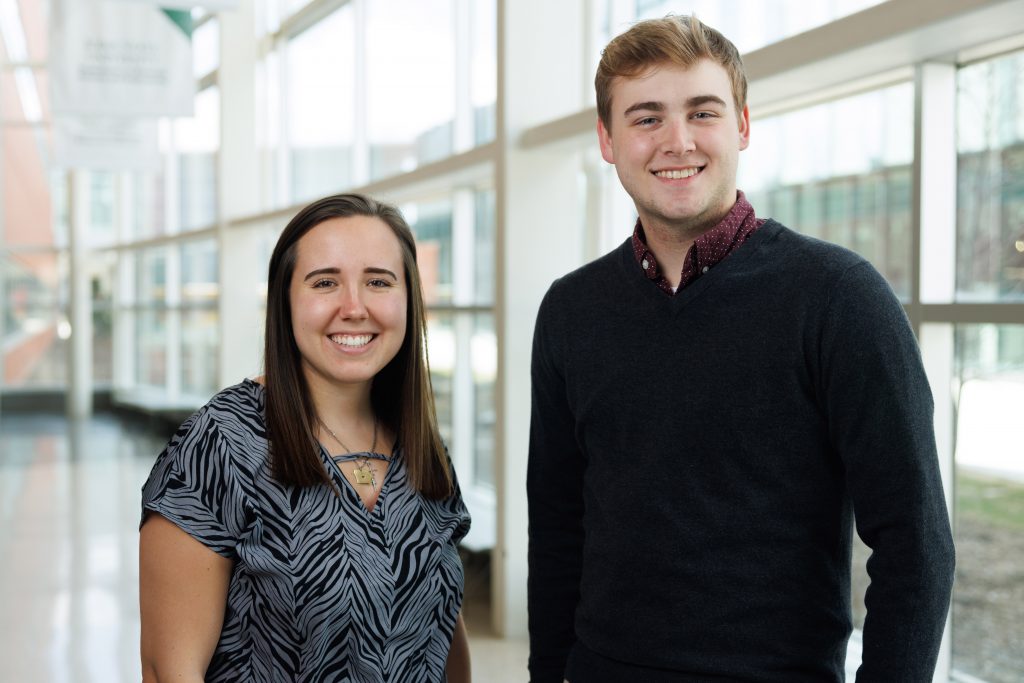 A young woman and young man pose together and smile for the camera