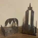 A metal cut out of pine trees and of a city skyline