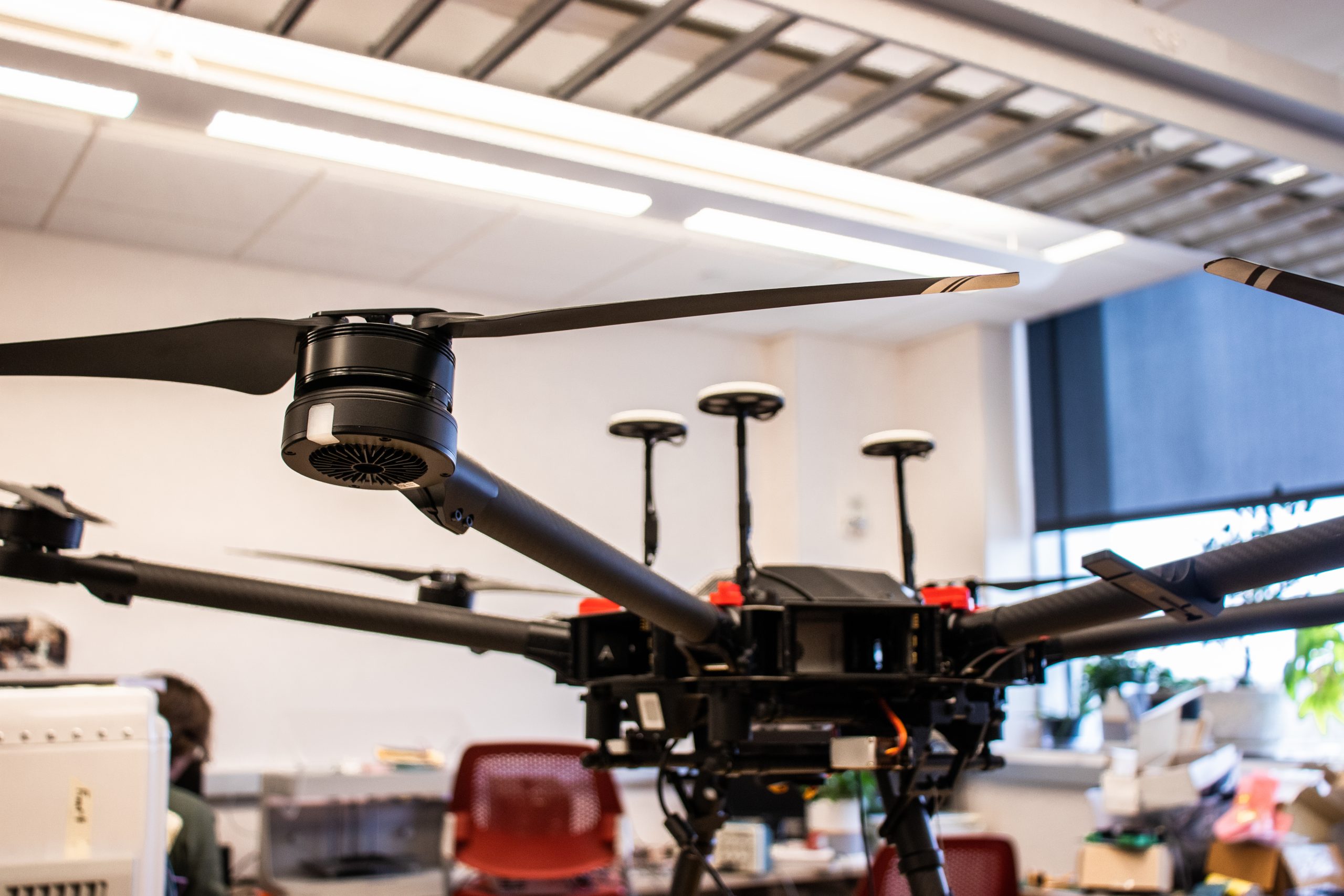 Photo of the drone in the lab. The drone is black with wings coming out of the arms on the drone