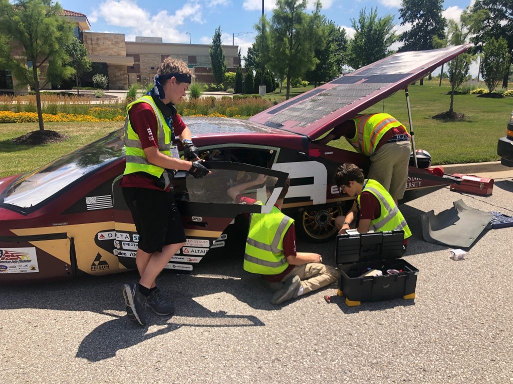 Team members work on their car