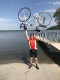 A man smiles and hold up his bicycle after completing RAGBRAI
