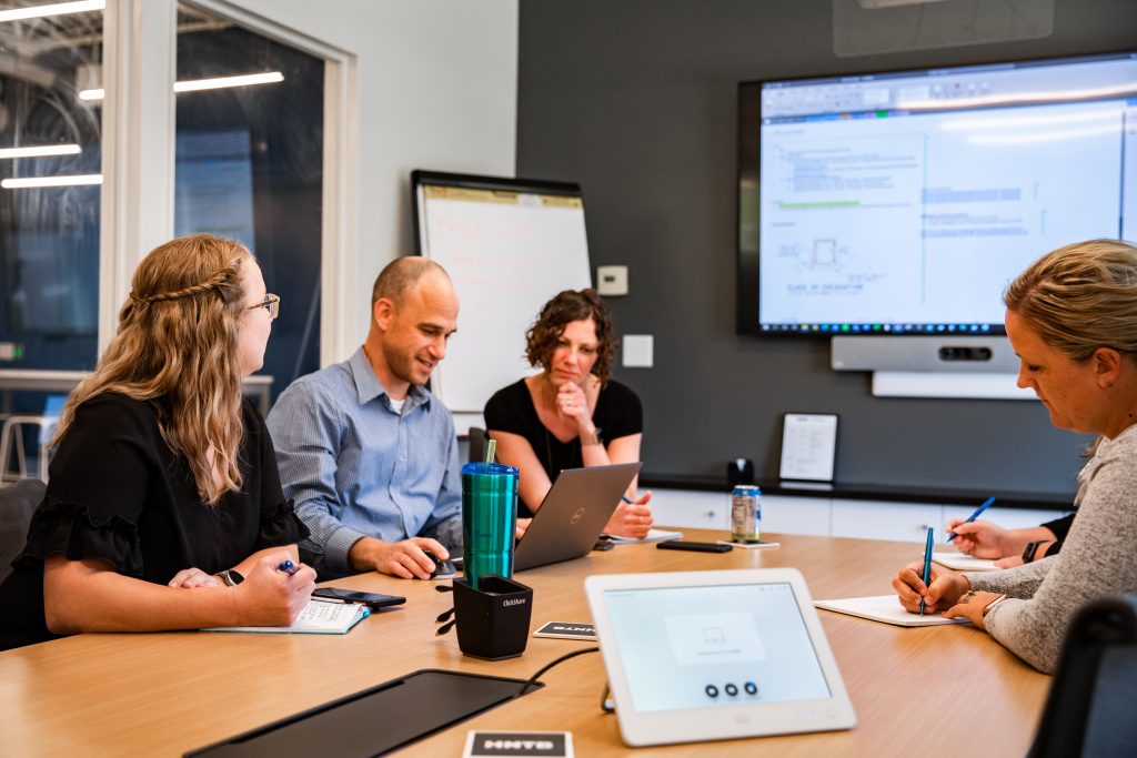 All four graduates sitting around a table collaborating on a project