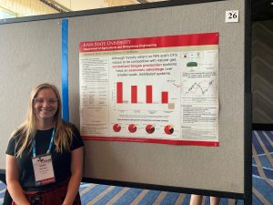 Photo of student smiling next to research poster