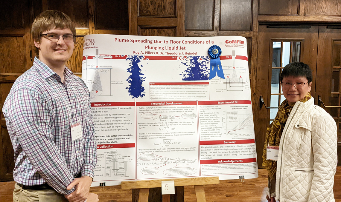 Two researchers stand with a research poster