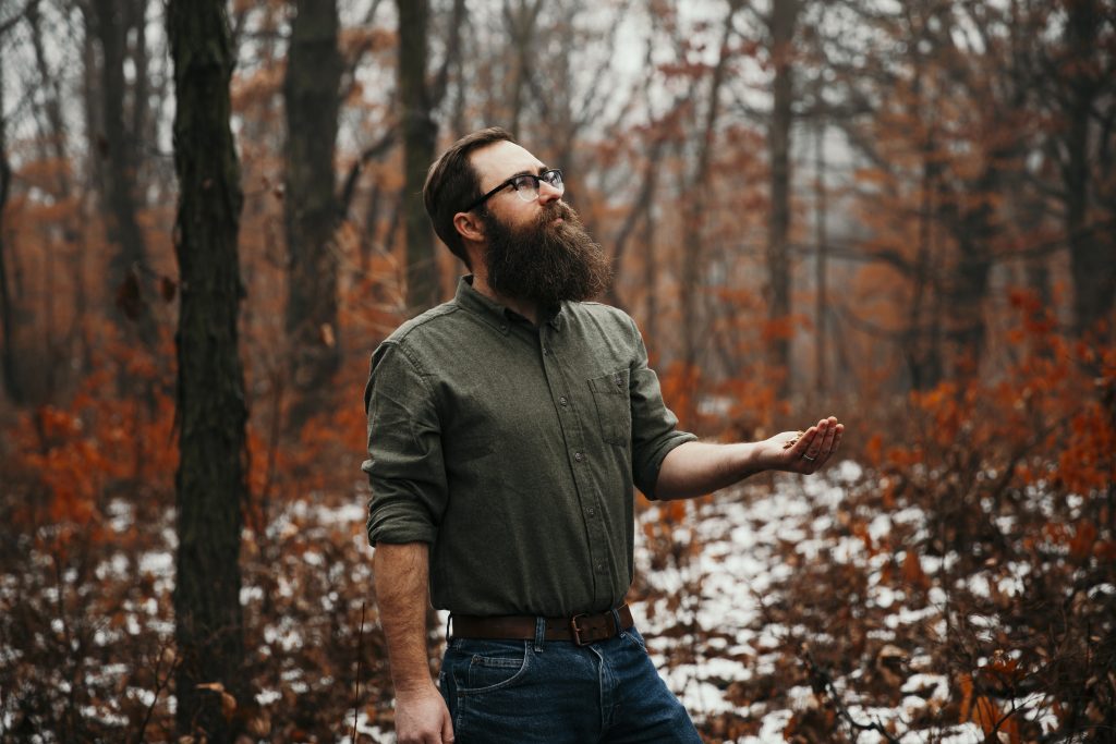Assistant professor Billy Beck in a forest at Ledges State Park with woodchips in his hand