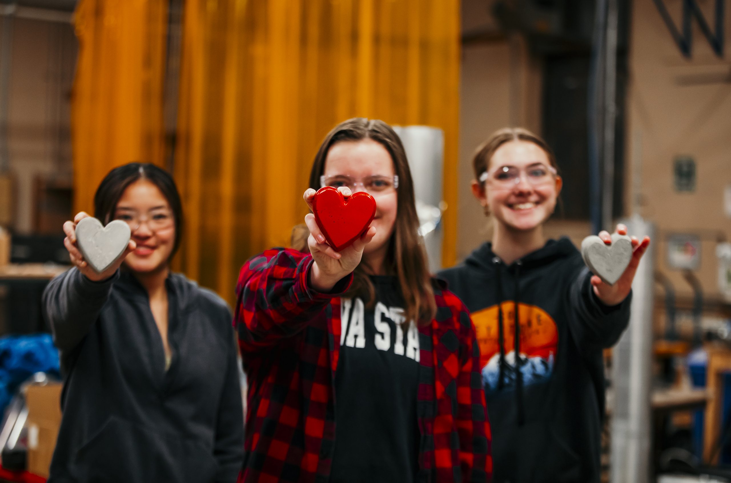 Three CCEE students holding concrete hearts towards the camera